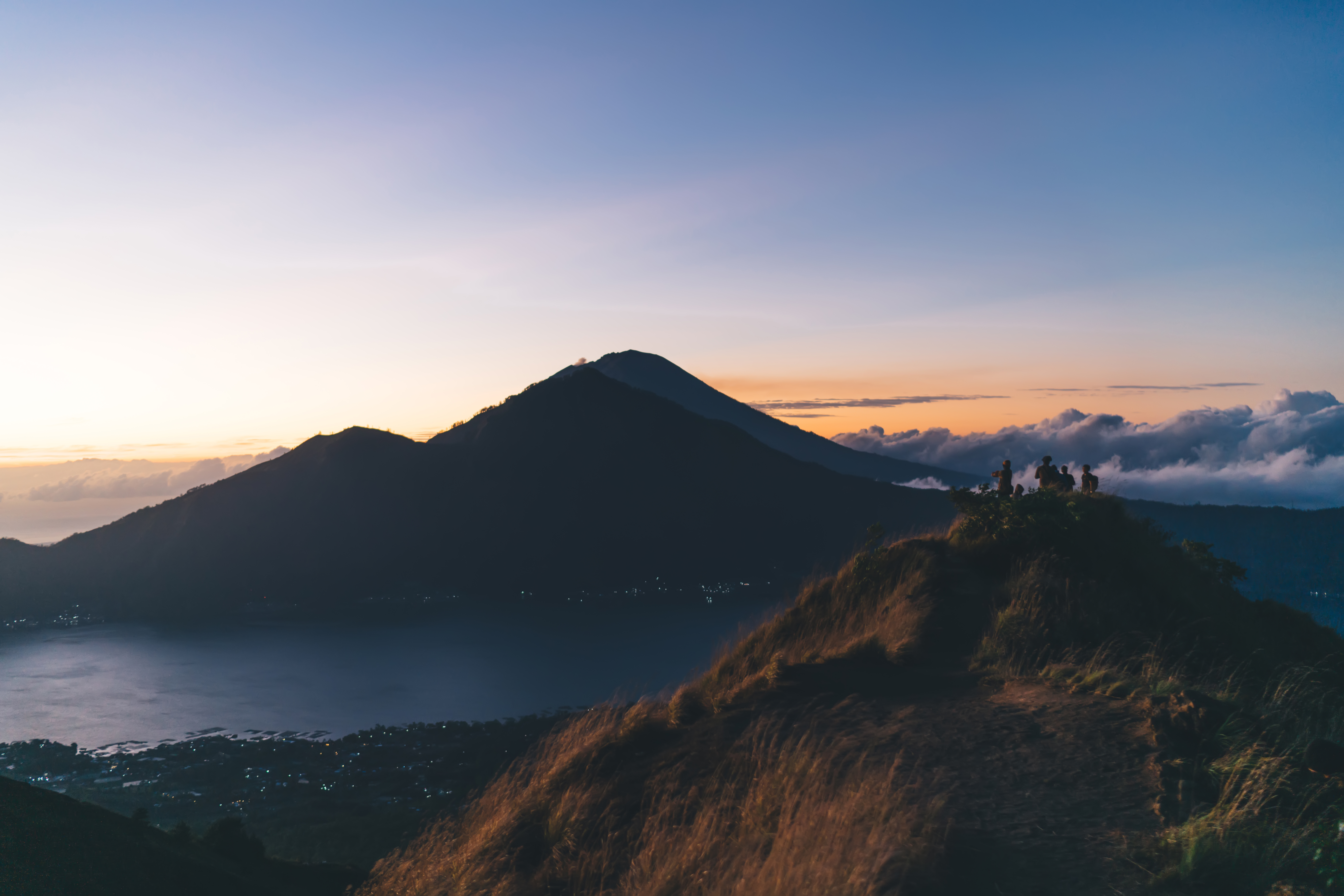 Scenic view of group of people admiring sunset from mountain peak together while on hiking trip through highlands at dusk